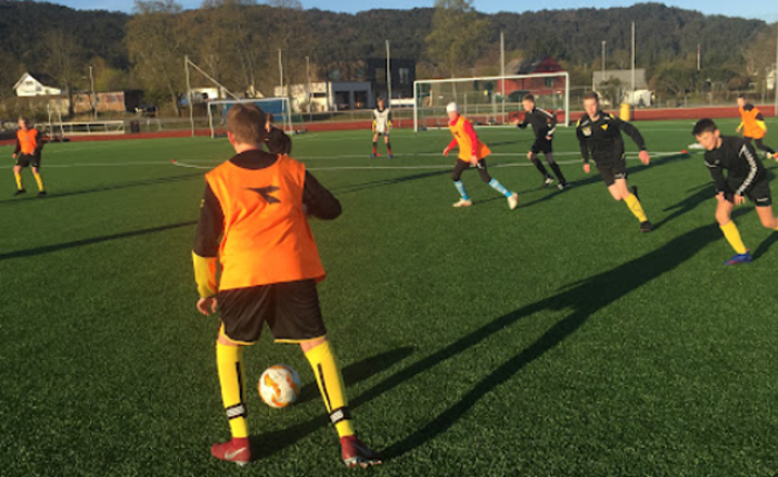 Fotballsperarar på fotballbane, spelaren som er nærmast står med ryggen til kamera.